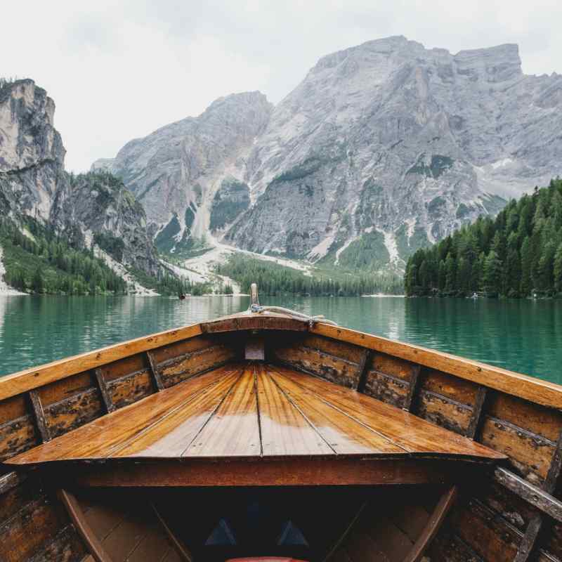 Get a new perspective on life, looking at things from a different view showing a photo of a boat in a lake looking at mountains surrounded by trees - how are you looking at your life?